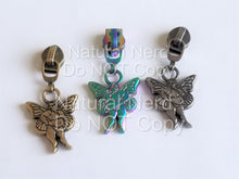 Load image into Gallery viewer, Three zipper pulls with a fairy design. The fairy is depicted as a chubby figure with wings. The zipper pulls are in three different finishes: antique brass, iridescent rainbow, and antique nickel.
