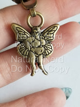 Load image into Gallery viewer, A gold-toned metal charm featuring a fairy with wings. The fairy is depicted with a full figure and has a round face with a slight smile. The charm is attached to a metal zipper pull.