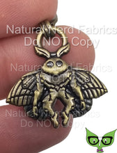 Load image into Gallery viewer, A bronze-colored metal zipper pull featuring a mothman design.