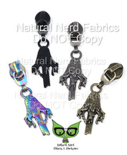 Load image into Gallery viewer, Four zipper pulls with a dripping inky cap mushroom design. The pulls are in black, silver, rainbow and antique brass.