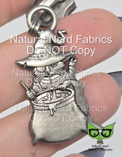 Load image into Gallery viewer, An antique silver zipper pull featuring a cat with an eyepatch wearing a robe and witch's hat, stirring a bubbling cauldron.