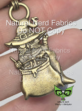 Load image into Gallery viewer, A bronze zipper pull featuring a cat with an eyepatch wearing a robe and witch's hat, stirring a bubbling cauldron.