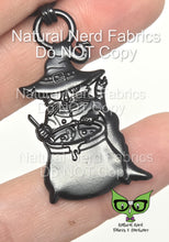 Load image into Gallery viewer, A matte black zipper pull featuring a cat with an eyepatch wearing a robe and witch's hat, stirring a bubbling cauldron.