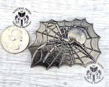 Load image into Gallery viewer, An antique silver-colored metal spider web magnetic snap design with a spider in the center. The spider and web are detailed with intricate lines. The design is rectangular and has a vintage or antique appearance. A US quarter is included as a size reference.