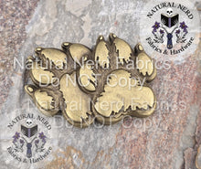 Load image into Gallery viewer, bronze paw print magnetic snap design on a textured surface with 'Natural Nerd' branding.