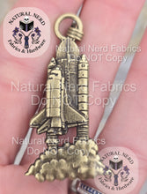 Load image into Gallery viewer, Hand holding a bronze space shuttle zipper pull.