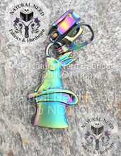 Load image into Gallery viewer, Matte rainbow rabbit-in-a-hat zipper pull on a stone surface with 'Natural Nerd' branding.