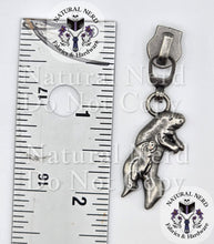 Load image into Gallery viewer, An antique nickel zipper pull with a momma and baby manatee designshown next to a ruler for scale.