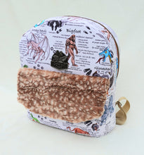 Load image into Gallery viewer, A backpack made with a cryptid-inspired fabric, with a fuzzy faux fur front pocket flap and a bronze plate that reads "Crafted by a cryptid."