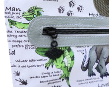 Load image into Gallery viewer, A close up of a black mothman zipper pull installed pn a white zipper with black teeth. The zipper is installed on a cryptid inspired handbag.
