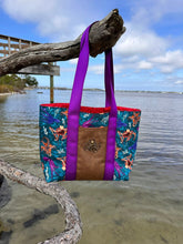 Load image into Gallery viewer, a tote bag featuring an octopus design hanging on a tree branch in front of the ocean