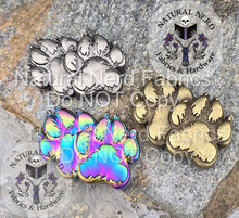 Load image into Gallery viewer, Metal paw-shaped magnetic snaps in antique silver, matte rainbow, and antique bronze on a stone surface with 'Natural Nerd' branding.
