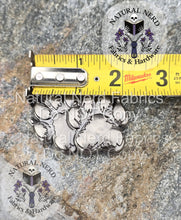Load image into Gallery viewer, antique nickel paw print snap with a measuring tape for scale on a textured surface, featuring 'Natural Nerd Fabrics &amp; Hardware' branding. The measuring tape shows the snap is two inches wide
