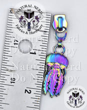 Load image into Gallery viewer, close up of a matte rainbow colored jellyfish zipper pull next to a ruler for scale. The ruler shows the pull is approximately 2 inches long including the zipper head. The jellyfish itself is about one inch long.
