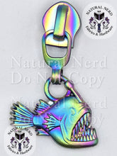 Load image into Gallery viewer, An matte rainbow metal angler fish zipper pull with a wide-open mouth showing sharp teeth. The image features 'Natural Nerd Fabrics &amp; Hardware' watermarks on a white background.
