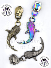 Load image into Gallery viewer, Three whale shark-shaped metal zipper pulls with different finishes: antique bronze, iridescent rainbow, and silver, shown on a white background with 'Natural Nerd Fabrics &amp; Hardware' watermarks.

