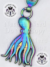 Load image into Gallery viewer, A rainbow-toned metal octopus zipper pull with detailed tentacles and suction cup patterns, shown on a white background with 'Natural Nerd Fabrics &amp; Hardware' watermarks.
