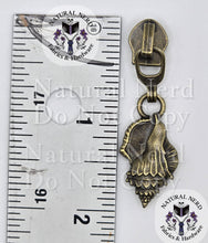 Load image into Gallery viewer, An antique bronze shell zipper pull with a detailed textured pattern, shown next to a metal ruler for scale on a white background with brand watermarks.
