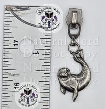 Load image into Gallery viewer, A silver-toned metal zipper pull shaped like a seal, shown next to a ruler for scale on a white background. The image includes repeated 'Natural Nerd Fabrics &amp; Hardware' watermarks.
