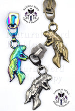 Load image into Gallery viewer, Three zipper pulls with a momma and baby manatee design in antique nickel, bronze, and matte rainbow finishes.
