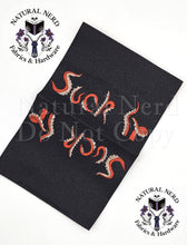 Load image into Gallery viewer, An open black fabric tag with the phrase 'Suck It' embroidered in red and white tentacle shaped letters on BOTH sides, shown with an overlaid watermark text from Natural Nerd Fabrics &amp; Hardware.
